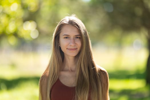 Young woman with long blonde hair is smiling outdoors on a sunny day