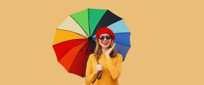 Autumn color style, beautiful happy cheerful young woman holding colorful umbrella, stylish joyful girl in french beret hat, yellow sweater on brown studio background