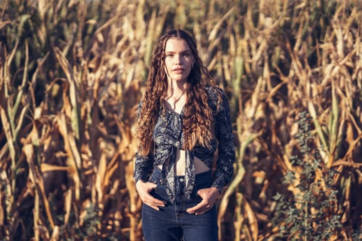 A stunning model is posing gracefully in a beautiful cornfield, showcasing a casual yet chic outfit in the warm glow of natural light that enhances her elegance and confidence in the moment