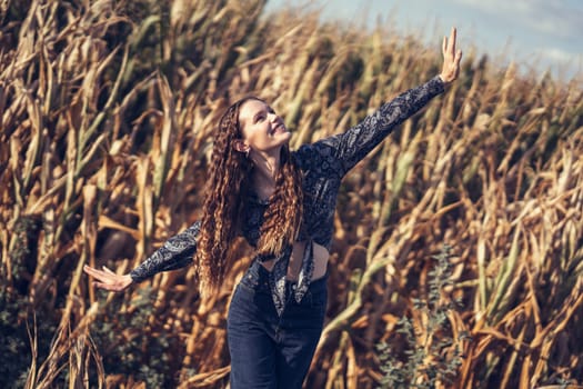 A young woman expresses her sheer joy while surrounded by a beautiful cornfield, dancing playfully and carefree amidst the tall golden stalks under a stunningly clear blue sky filled with sunshine
