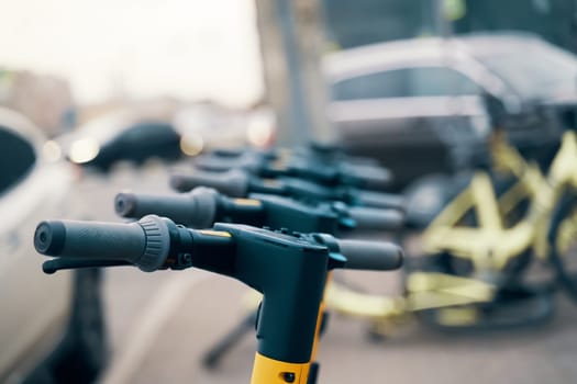A line of electric blue electric scooters with automotive tires parked in a lot, showcasing engineering and recreation in machine design