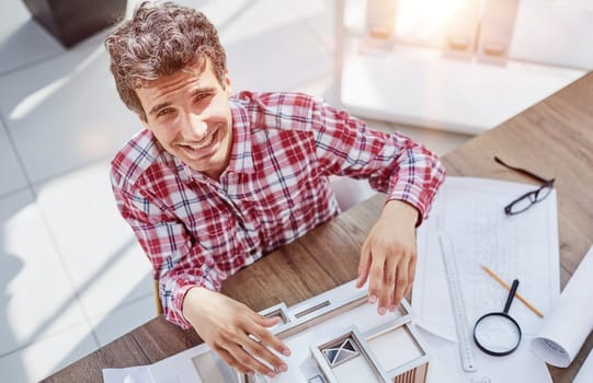 Male architect holding and working on model of architectural house top view