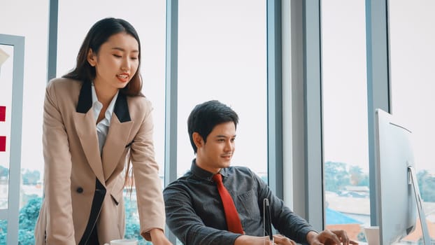 Two business people talk project strategy at office meeting room. Businessman discuss project planning with colleague at modern workplace while having conversation and advice on financial report. Jivy