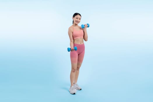 Vigorous energetic woman doing dumbbell weight lifting exercise on isolated background. Young athletic asian woman strength and endurance training session as body workout routine.