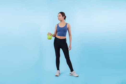 Vigorous energetic woman doing kettlebell weight lifting exercise on isolated background. Young athletic asian woman strength and endurance training session as body workout routine.