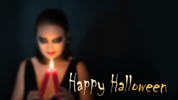 Blurred silhouette of woman in image of witch with burning candle in hands on black background with inscription Happy Halloween, concept of Halloween, copy space, banner