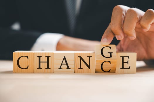 Businessman hand turns CHANGE into CHANCE on wood block. Success, strategy, business concepts resonate. Vintage table texture enriches composition. Change is portrayed.