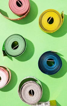 Dieting concept. colorful measuring tapes top view on bright green background, flat lay, pattern