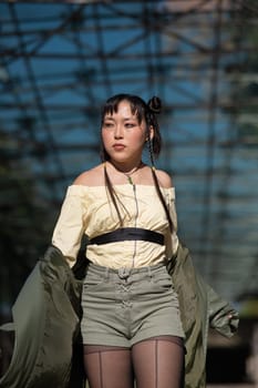 A beautiful Asian woman in shorts and a green leather coat comes out of the subway