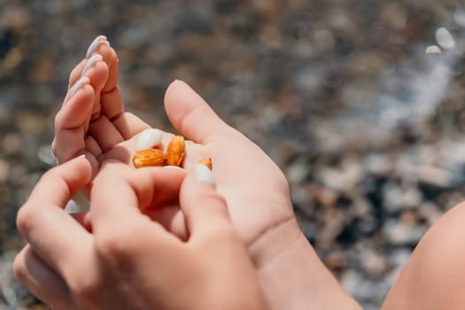 Woman eating milky almond nuts. A young caucasian woman choping fresh green almond after morning fitness yoga near sea. Only hands are visibly. Healthy vegan food. Slow motion. Close up