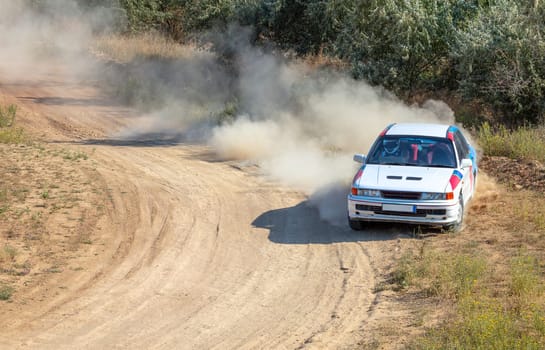 Sunny summer day. Sports car makes a sharp turn on a dirt track