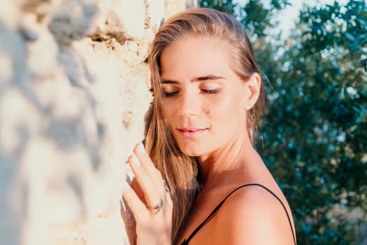 Woman travel sea. Young Happy woman in a long red dress posing on a beach near the sea on background of volcanic rocks, like in Iceland, sharing travel adventure journey