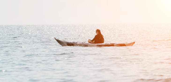 Happy smiling woman in kayak on ocean, paddling with wooden oar. Calm sea water and horizon in background
