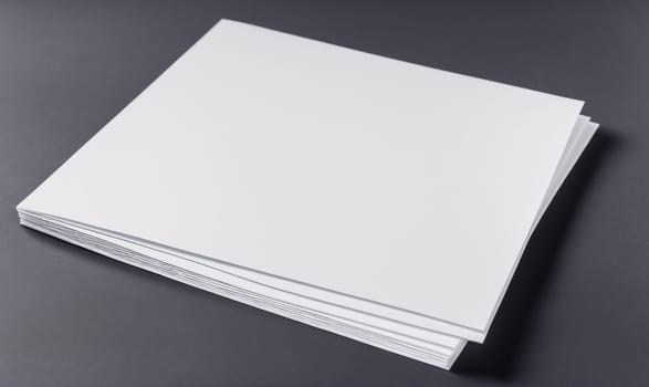A stack of blank white paper lies flat on a gray surface. The paper is neatly stacked, and the edges are slightly visible.