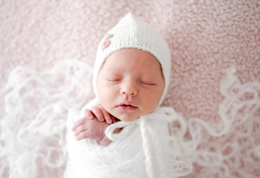 Sleeping Newborn Baby Wrapped In Swaddle Is A Studio Photo Of A Little Girl