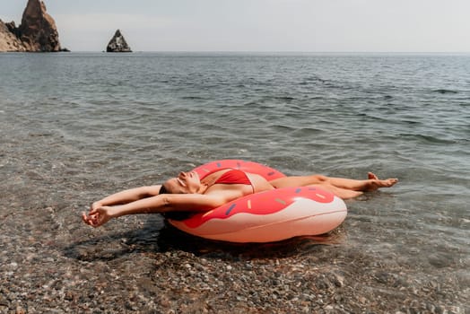 Summer Vacation Woman in hat floats on an inflatable donut mattress, a water toy swim ring. Unrecognizable young woman relaxing and enjoying family summer travel holidays vacation on the sea
