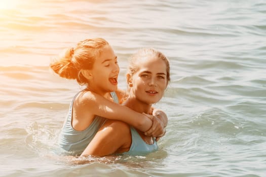 A young girl in blue swimsuit is having fun with her mom in the sea, they are laughing and splashing water, creating a joyful atmosphere.