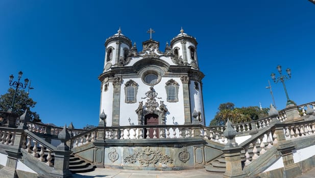 A Baroque-style church with an ornate facade and twin towers stands against a blue sky.