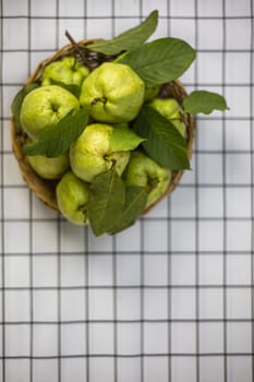 Green guava in the bamboo basket on the table.