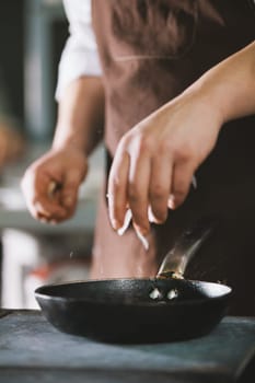 The cook adds spices and onion to food close up