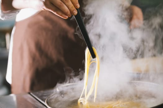 Chef cooking spaghetti in restaurant, close-up view