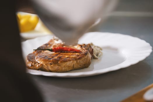 Chef serves meat on the plate close-up