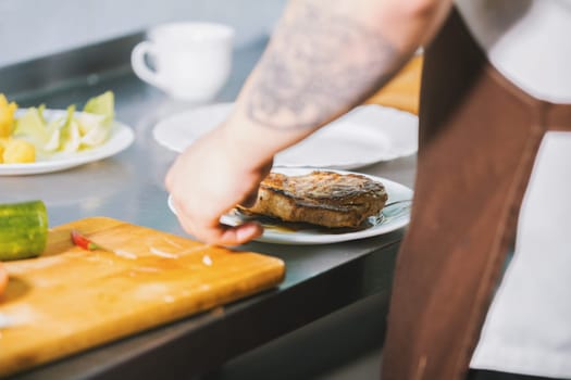 Chef serves meat on the plate in restaurant close-up