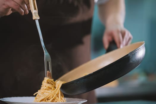 Chef serves spaghetti on the plate in restaurante close-up