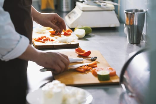 Chef chops vegetables for salad in commercial kitchen close-up