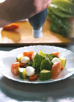Chef serves greek salad on the plate in restaurant close-up
