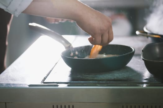 chef is frying meat and vegetables in a pan close-up