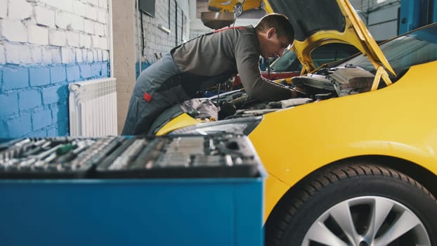 Mechanic in car service - repairing in engine compartment, close up