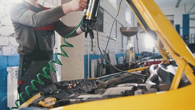 A mechanic checks the electrical in the hood of the car- repairing in engine compartment, close up