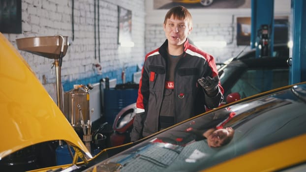 Portrait of a young car mechanic in overalls in a car workshop, portrait