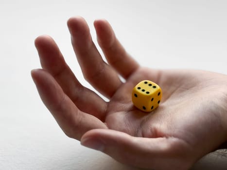 Open hand holding yellow dice for chance and luck concepts.
