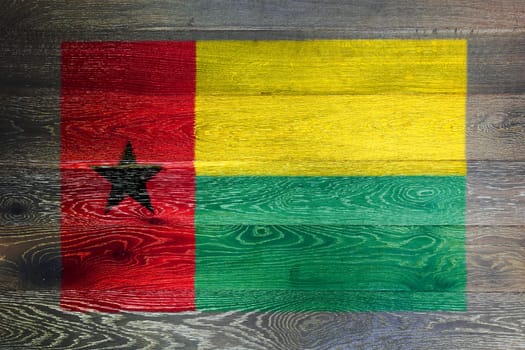 A Guinea-bissau flag on rustic old wood surface background red yellow green star black
