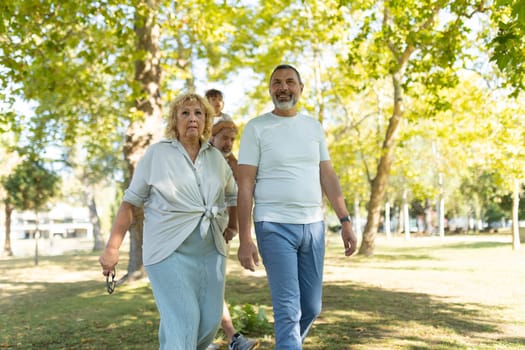 Family, spanning three generations, is enjoying a leisurely stroll through a sunny park