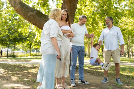 Multi-generation family is spending time together in a park, enjoying the outdoors and each other's company