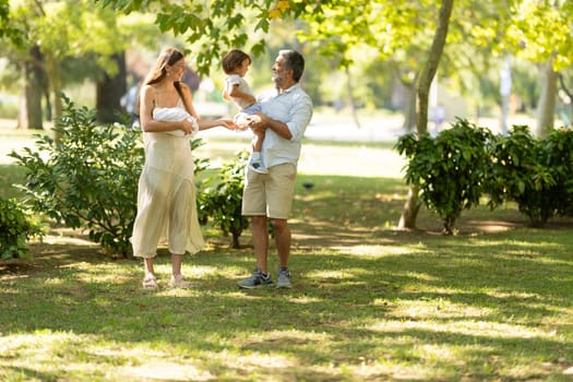 Family is enjoying a sunny day together, walking through a park