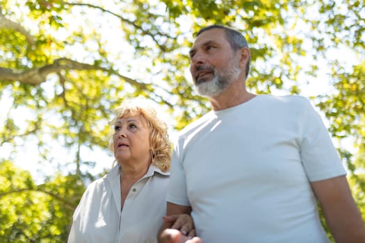 Senior couple is enjoying their retirement by taking a peaceful walk in the park on a sunny day