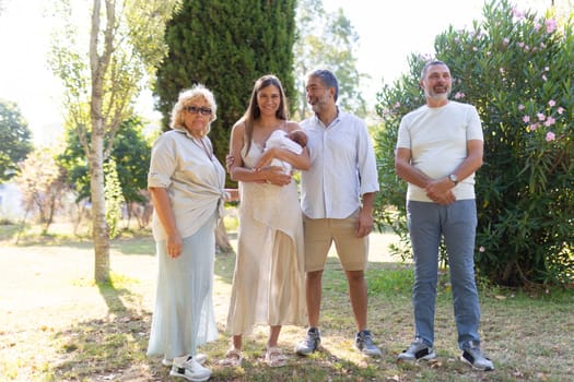Happy family is standing together in the park, celebrating the arrival of their newborn baby
