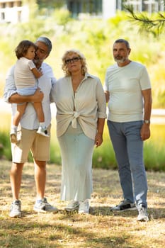 Family is posing for a photo in the park on a sunny day, enjoying the outdoors together