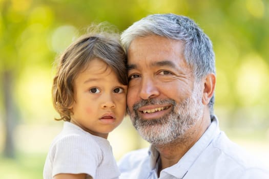 Happy grandfather and grandson spending time together in the park on a sunny day