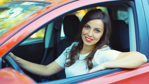 Portrait of happy smiling female driver sitting behind the wheel of car