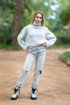 Attractive young woman is striking a pose while standing on a path in a park
