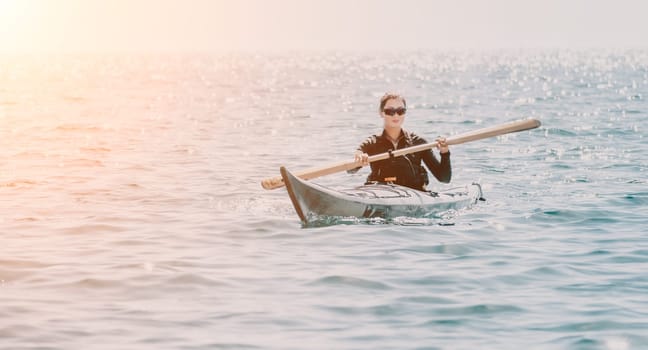 Happy smiling woman in kayak on ocean, paddling with wooden oar. Calm sea water and horizon in background