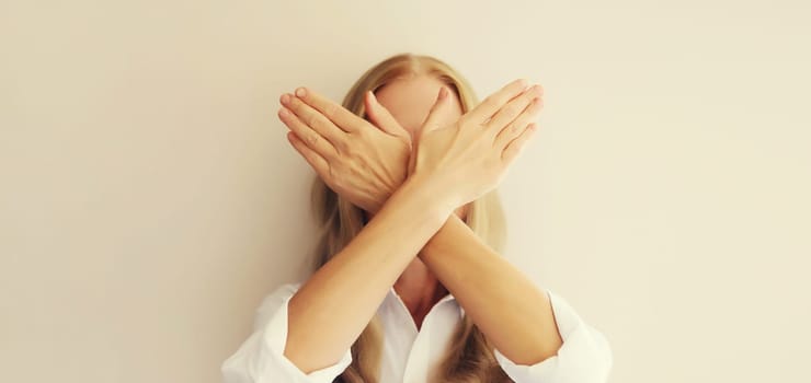 Upset woman shows stop, no or enough sign with palm of hand, refusal gesture, domestic violence.