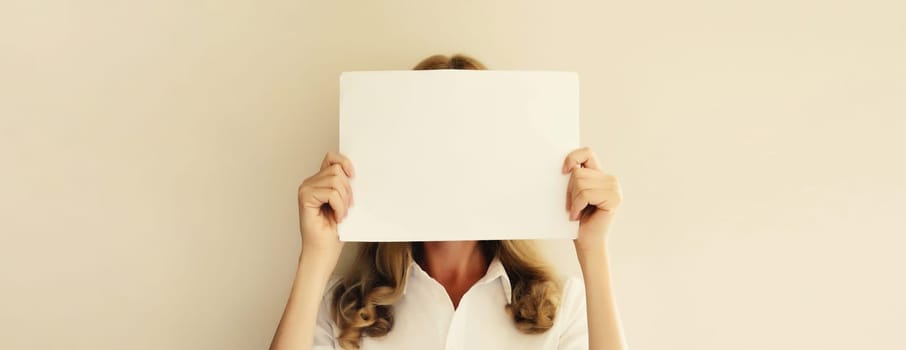 Woman showing and holding white blank sheet of paper document for advertising text blank copy space on studio background