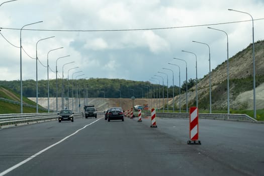 A road with a red and white cone on the side of it. The road is empty and there are no cars on it