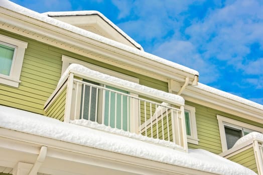 Top of residential building with patio and roof covered with snow.